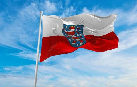Flag of Thuringia, state at cloudy sky background on sunset, panoramic view.  Stock Illustration