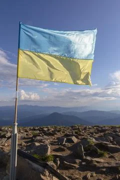 The flag of Ukraine flutters in the wind on top of a mountain in the Carpat.. Stock Photos