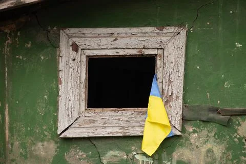 The flag of Ukraine hangs on the window of a destroyed residential building, Stock Photos