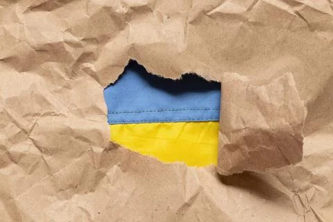 Flag of Ukraine seen through torn craft paper as symbolism, freedom Stock Photos