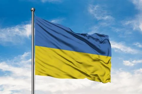 Flag of Ukraine waving in the wind against white cloudy blue sky. Ukrainian f Stock Photos