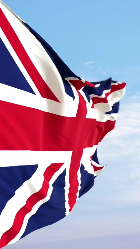 The flag of the United Kingdom waves in slow motion against a blue sky. Stock Footage 330876727