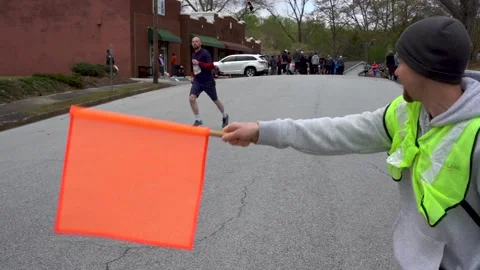 Flag waver directing road race runner to correct route Vidéo 194401204