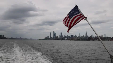 A flag waves from a ferry with the New York City skyline Stock Footage 158130408