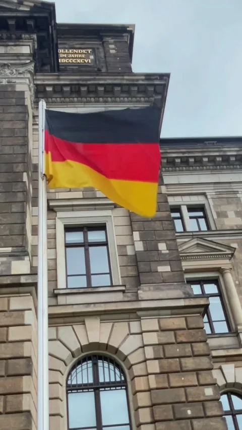 Flag waving in front of historic building in Germany during clear day Stock Footage 329320119