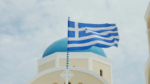 Flag waving in front of Saint George Church dome, Oia, Santorini, Greece Stock Footage 220222774