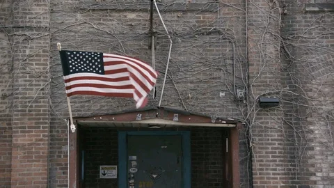 Flag waving on industrial brick building with vines Stock Footage 89945046