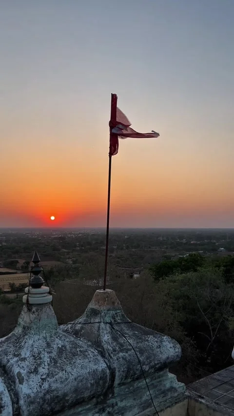 Flag waving on a temple rooftop against a beautiful orange sunset 스톡 동영상 333451681