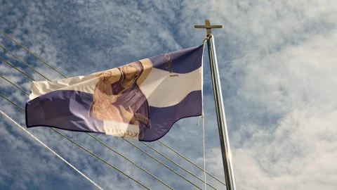 Flag waving under clear sky with cross atop pole in background Stock Footage 347325332