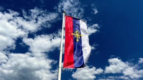 A flag is waving in the wind against a blue sky with clouds Stock Footage 283509519