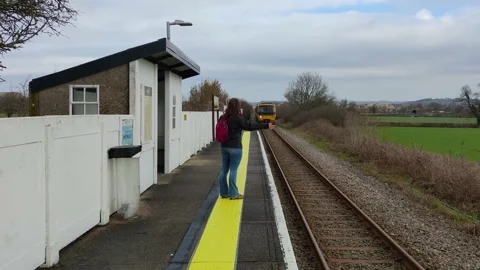 Flagging down the train at small british request stop train station 動画素材 238698420