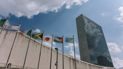 Flags and UN building facade with clouds in Manhattan - New York - USA Stock Footage 114404458