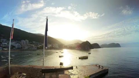 Flags and view on the shore and hills in morning sunlight in Petrovac Stock Footage 168185605