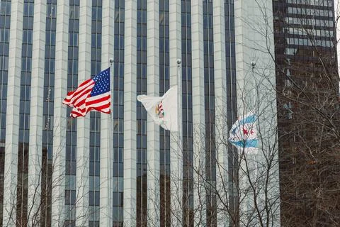 Flags are displayed in front of a tall building in Chicago on a clear day w.. Stock Photos