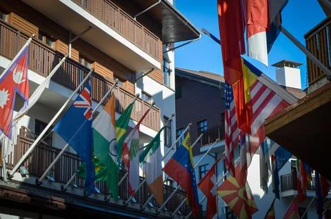 Flags of different countries against the background of sunlit buildings Stock Photos