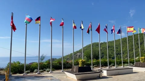Flags of different countries flutter against the backdrop of a green mountain, s Stock Footage 319998174