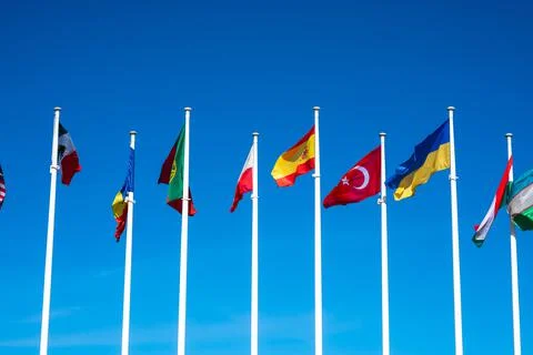 Flags of Different Countries Hang On Flagpoles Against Blue Sky. Flag of Spain Stock Photos