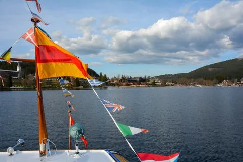 Flags from different countries on a ship in front of a town on Lake Titisee w Stock Photos