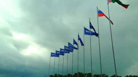 Flags of different countries stand tall under a cloudy sky at a location in Bela Stock Footage 337525344