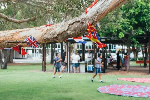 Flags of different countries in the tree branch with blured people in park doing Stock Photos