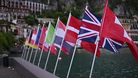 Flags of different countries waving in the wind by Lake Garda Stock Footage 305556239