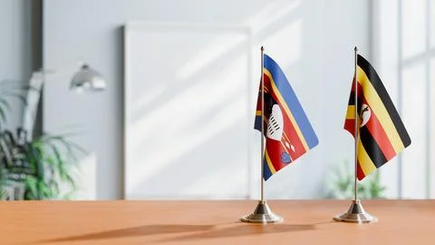 FLAGS OF ESWATINI AND UGANDA ON TABLE Stock Photos