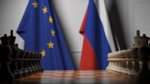Flags of the EU and Russia behind chess board. The first pawn moves in the Stock Footage 115470191