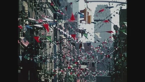 Flags fluttering overhead above a street in Little Italy in New York, 1971 Stock Footage