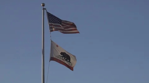 Flags fly in the wind blue skies behind Stock Footage 122331881