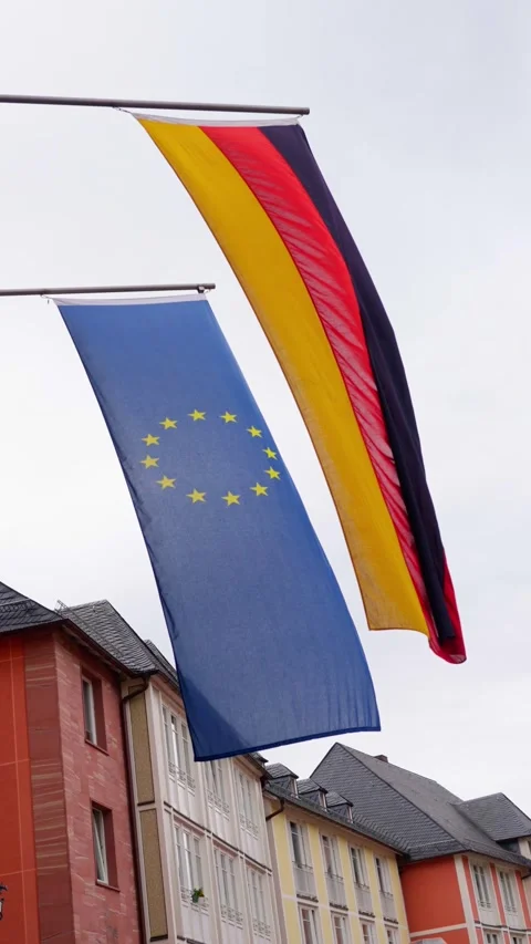 The flags of Germany and the EU flutter in the wind, symbolizing unity and Stock Footage 316818640