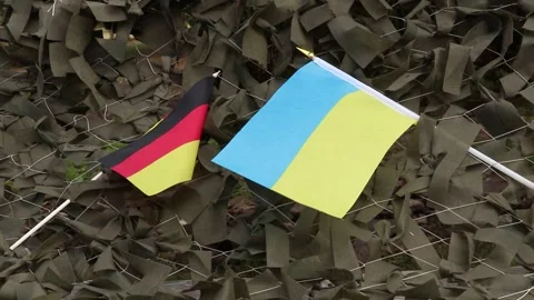 Flags of Germany and Ukraine attached to a camouflage military net made Stock Footage 316449948