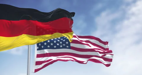 Flags of Germany and the USA waving in the wind on a clear day Stock Footage 334855849