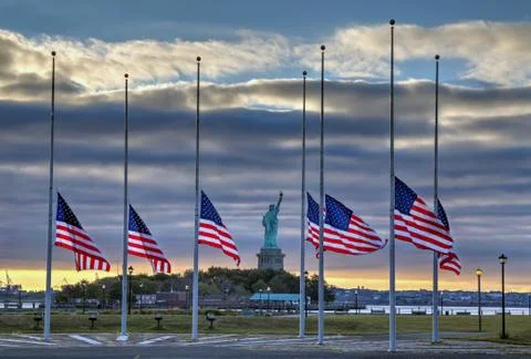 Flags at half staff in front of Statue of Liberty Stock Photos