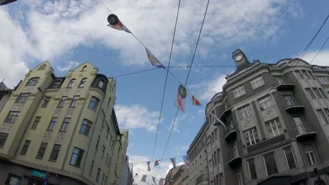 Flags Hanging Between Buildings in a busy city street on Festival 4k60fps Stock Footage 136220574