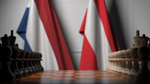 Flags of Netherlands and Austria behind pawns on the chessboard. Chess game or Stock Footage 116599747