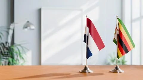 FLAGS OF NETHERLANDS AND ZIMBABWE ON TABLE Stock Photos