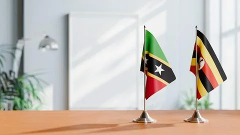 FLAGS OF SAINT KITTS AND UGANDA ON TABLE Stock Photos