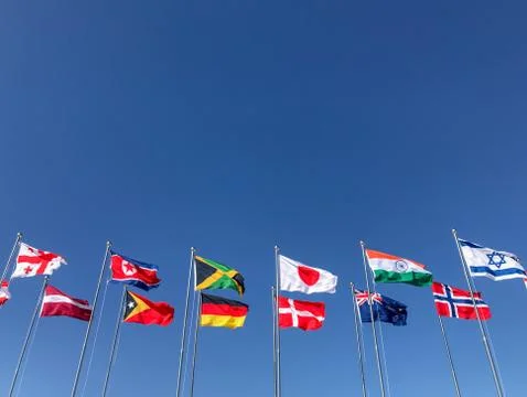 Flags of several countries waving in front of a blue sky Stock Photos