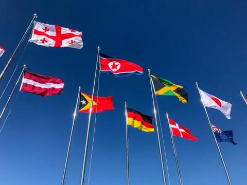 Flags of several countries waving in front of a blue sky Stock Photos