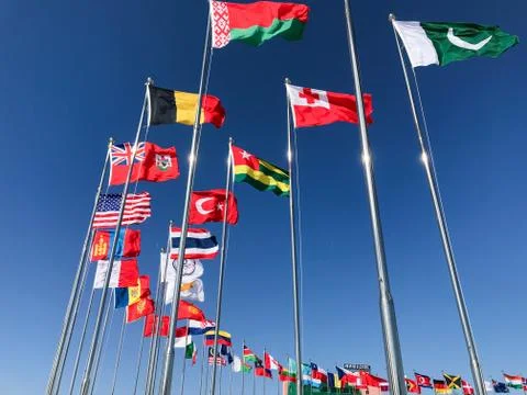 Flags of several countries waving in front of a blue sky Stock Photos