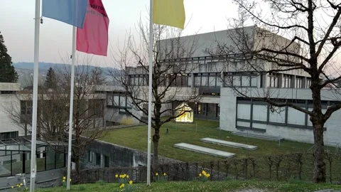 Flags of university with buildings and spring flowers. Stock Footage 176919543