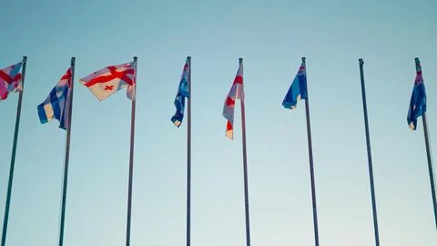 Flags of various countries waving against a clear blue sky Stock Photos