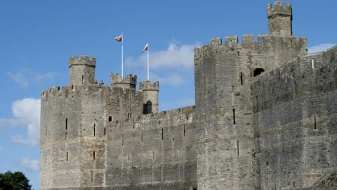 Flags wave clouds drift by ramparts Caernarfon Castle Wales Stock Footage 96029858