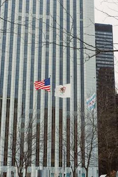 Flags wave in front of tall buildings in a city during winter near a public.. Foto stock