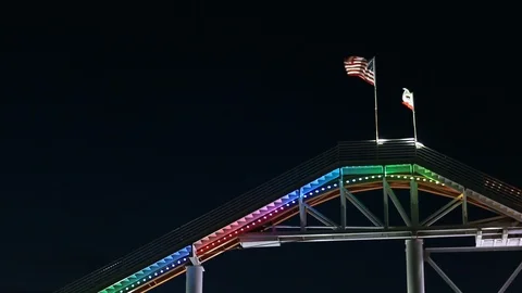 Flags waving atop colorful roller coaster at night Vidéo 99316329