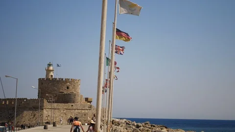Flags waving in the harbor with people walking around Video stock 129754902