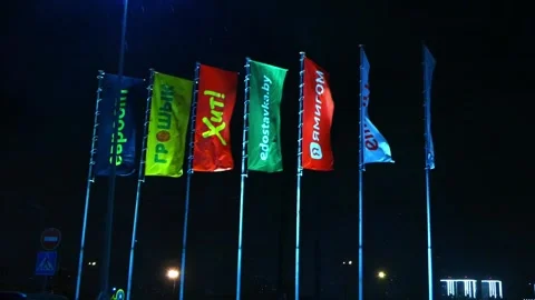Flags waving at night in a city location with bright lights in the background st Stock-Footage 325802949