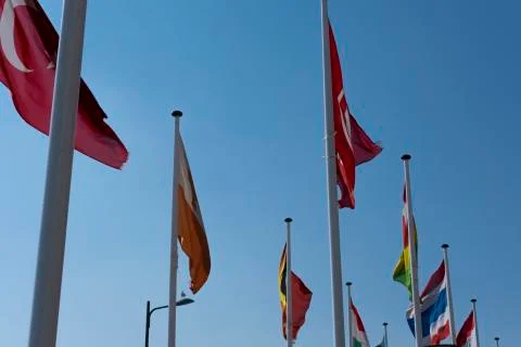 Flags waving in the wind on flagpoles equal distant apart against a blue sky Stock Photos