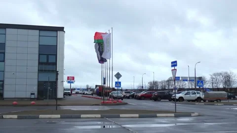 Flags waving in the wind at a parking lot near a shopping center on a cloudy day Stock Footage 337966130