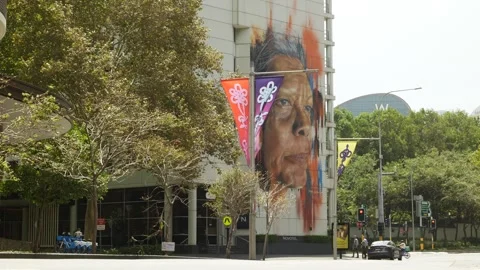 Flags in the wind and Aboriginal face mural on large Sydney building 6K Stock Footage 301421847